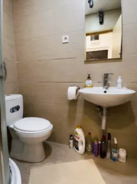 Manje kupatilo sa WC šoljom, umivaonikom i ogledalom obloženo keramičkim pločicama. - image 5