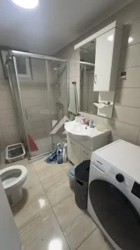 Bathroom equipped with a shower cabin, washbasin, toilet, and washing machine. - image 7