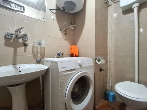Manje kupatilo obloženo keramičkim pločicama sa umivaonikom, veš mašinom i toaletom. - image 7