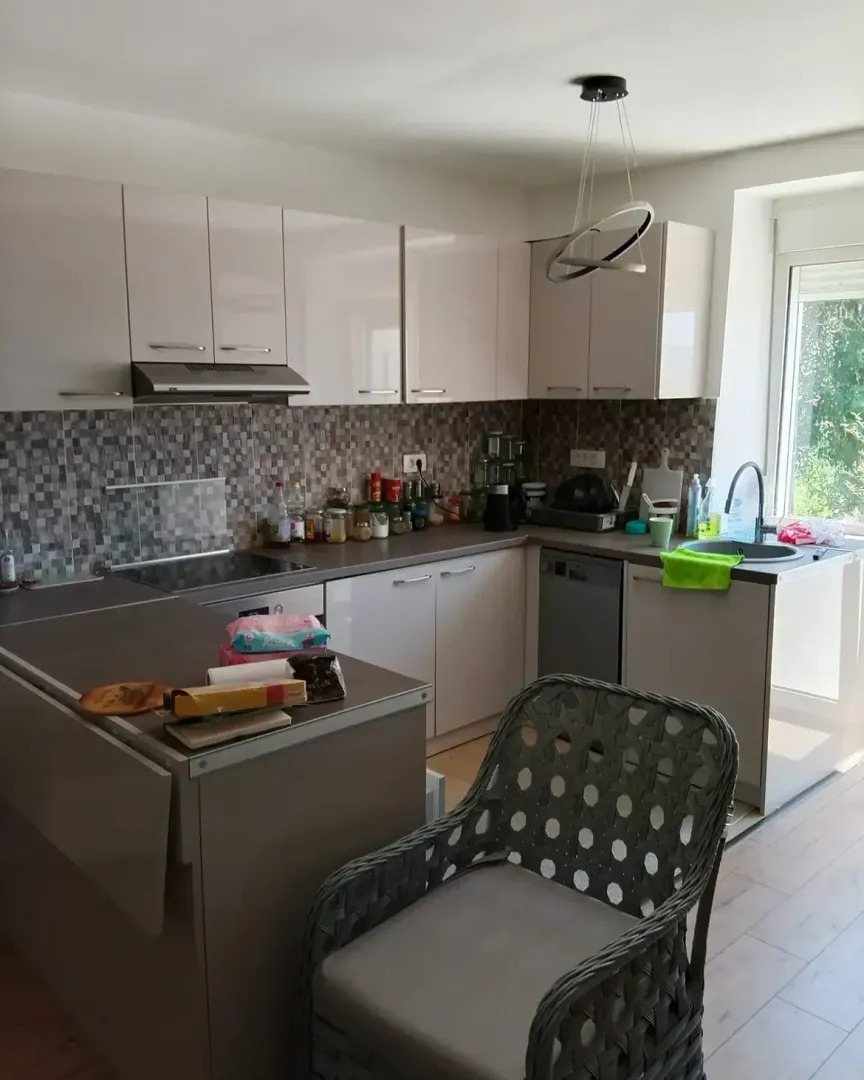 Modern kitchen with light-colored cabinets and a dining table.