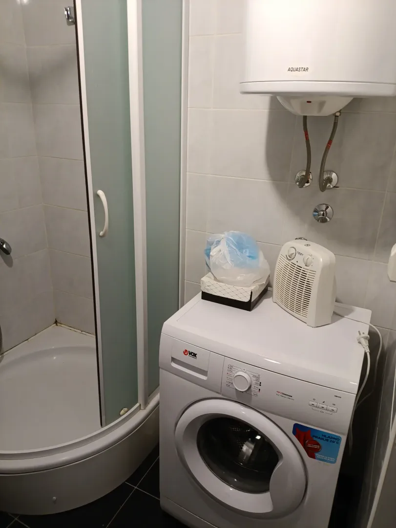 Manje kupatilo sa tuš kabinom i veš mašinom.