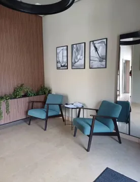 Living room with two armchairs, a small table, and pictures on the wall. - image 3
