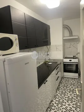 Small kitchen with black upper cabinets, white lower cabinets and a refrigerator. - image 20