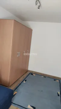 Manja soba sa velikim ormanom i plavim tepihom na podu. - image 2