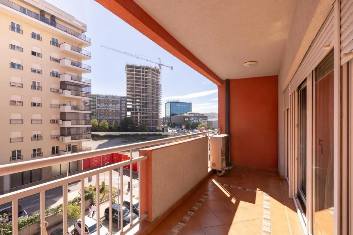 Natkriveni balkon sa pogledom na grad i okolne zgrade.