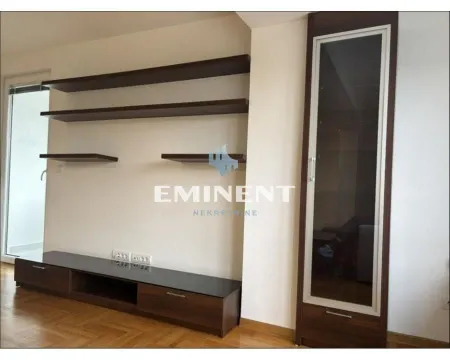 Dnevna soba sa zidnim policama i komodom za TV. - image 2