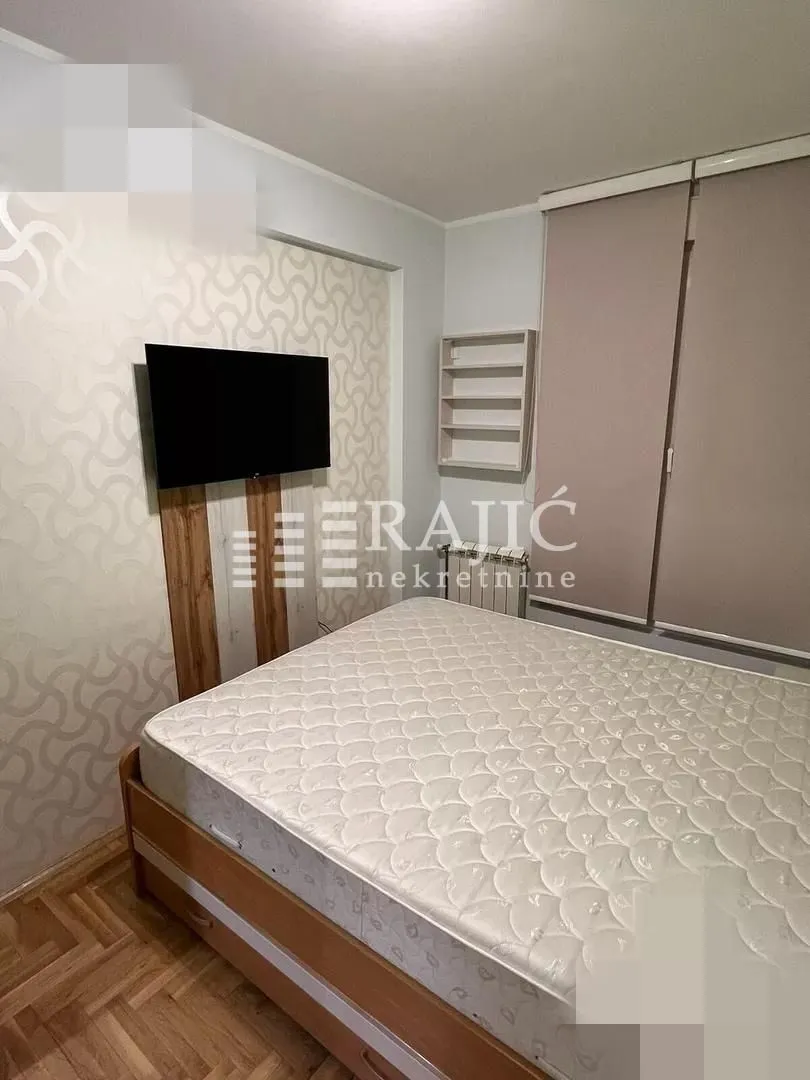 Bedroom with a double bed, wardrobe, and a wall-mounted TV.