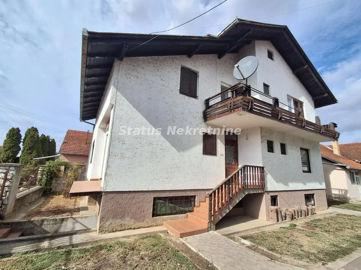 Pogled na spoljašnjost kuće sa stepeništem i balkonom.