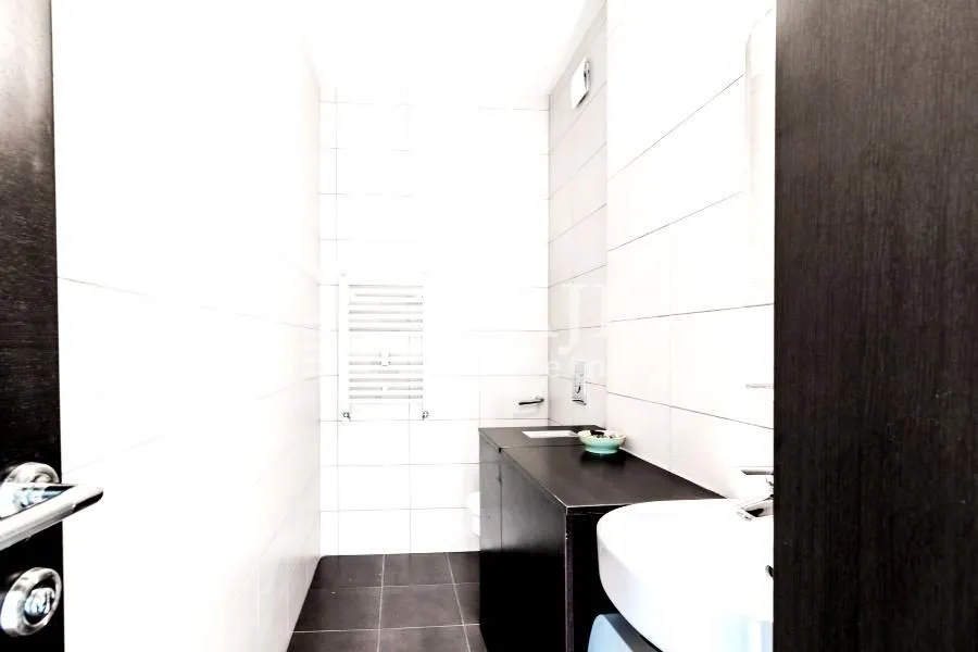 Modernly equipped bathroom with white tiles and dark elements.