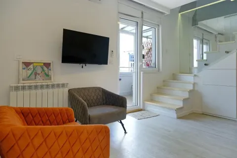 Dnevna soba sa foteljama, televizorom na zidu i stepeništem koje vodi na sprat. - image 8