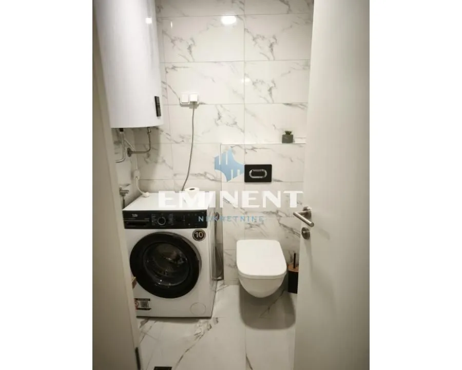 Small bathroom with a toilet, washing machine, and water heater.