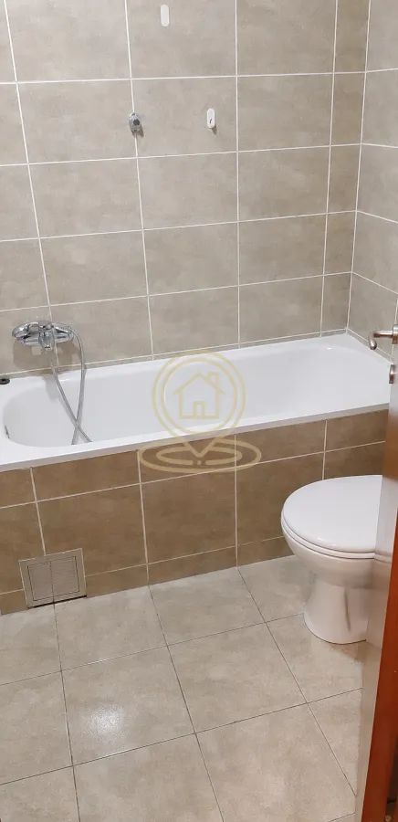 Kupatilo opremljeno kadom, slavinom i wc šoljom, obloženo keramičkim pločicama.