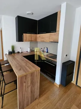 Small kitchen with wooden elements, black cabinets, and a dining bar. - image 4
