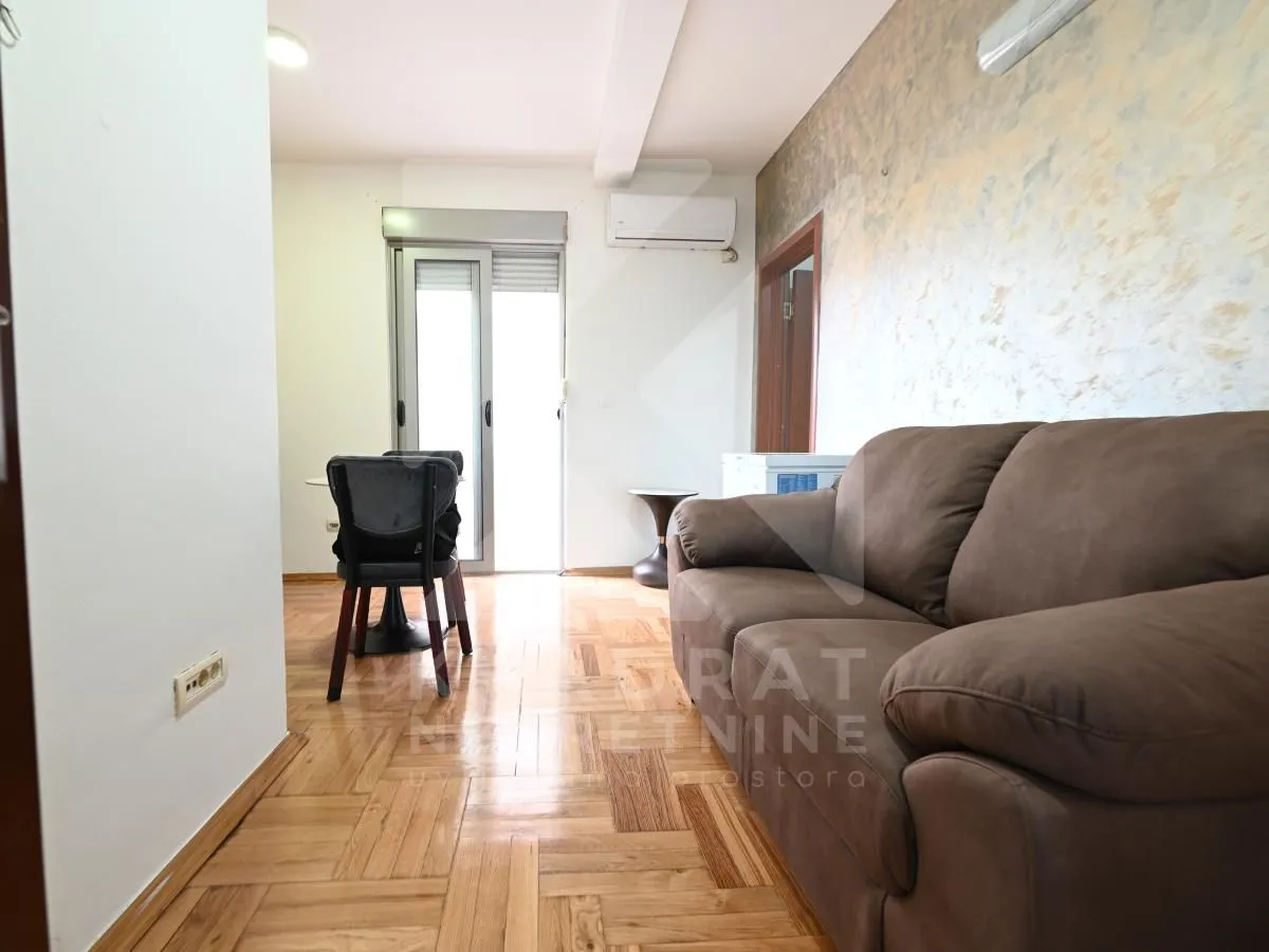 Living room with a sofa and a dining area in the background.