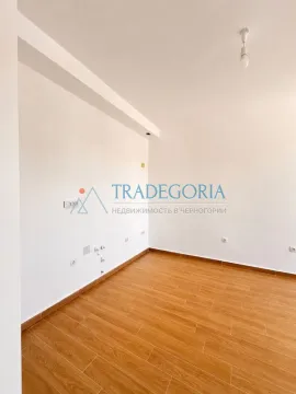 Prazna soba sa bijelim zidovima i drvenim podom. - image 2