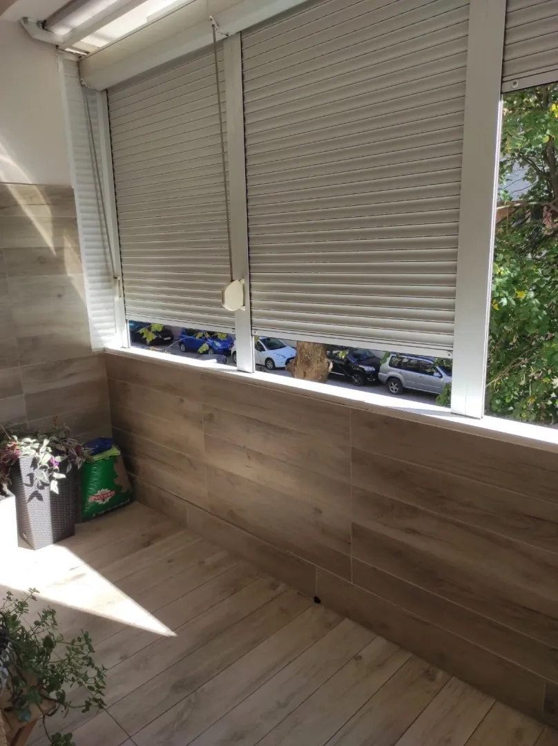 An enclosed balcony tiled with wood-look ceramics.