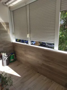 An enclosed balcony tiled with wood-look ceramics. - image 7
