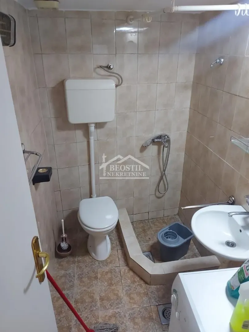 Manje kupatilo sa wc šoljom, umivaonikom i pločicama.