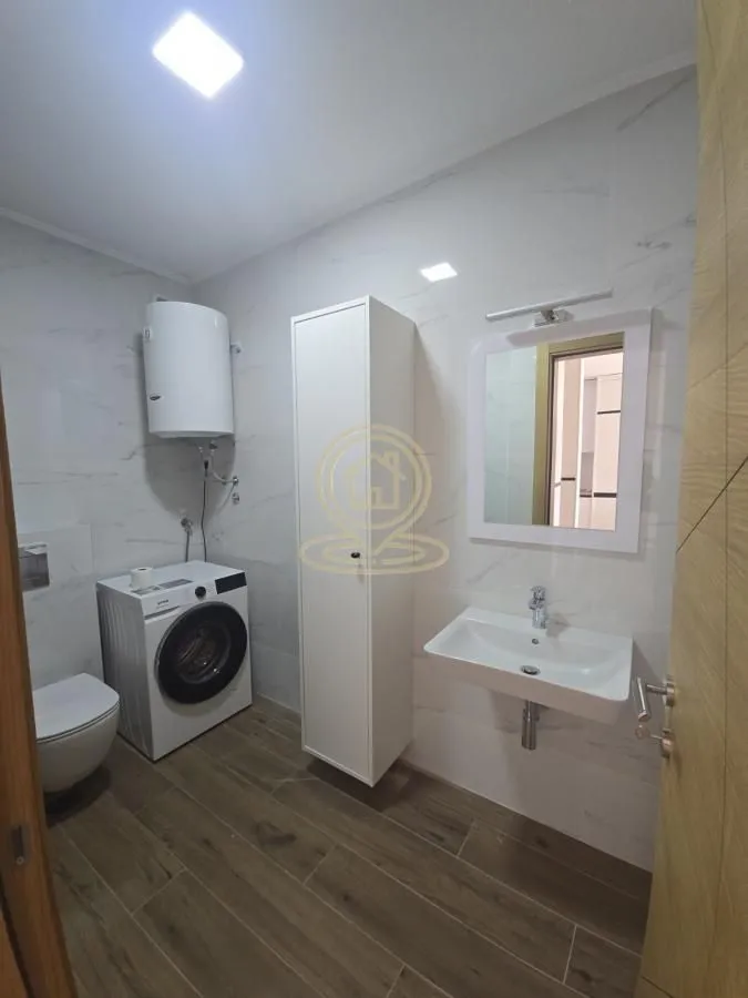 Moderno kupatilo sa umivaonikom, WC šoljom, mašinom za veš i bojlerom.