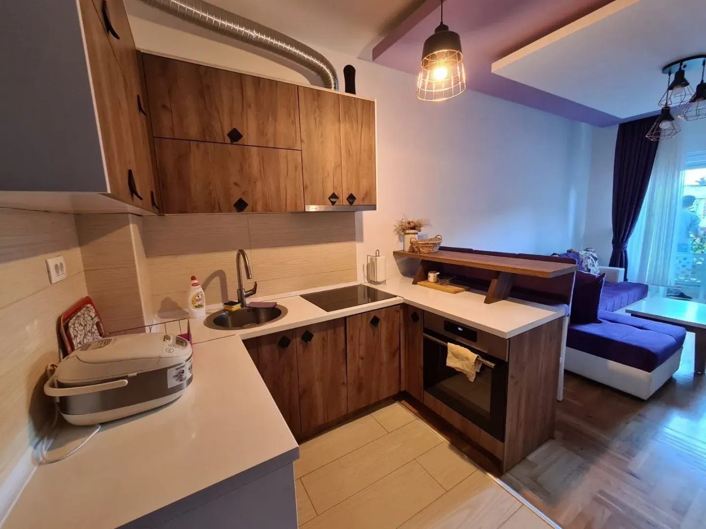 Small kitchen with wooden cabinetry integrated into the living room.