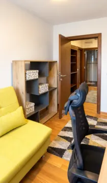Small room with a yellow sofa, office desk and shelving units. - image 12