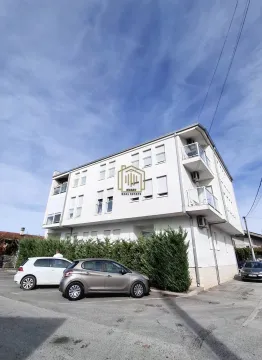 Pogled na spoljašnjost stambene zgrade sa parkingom i zelenilom. - image 2