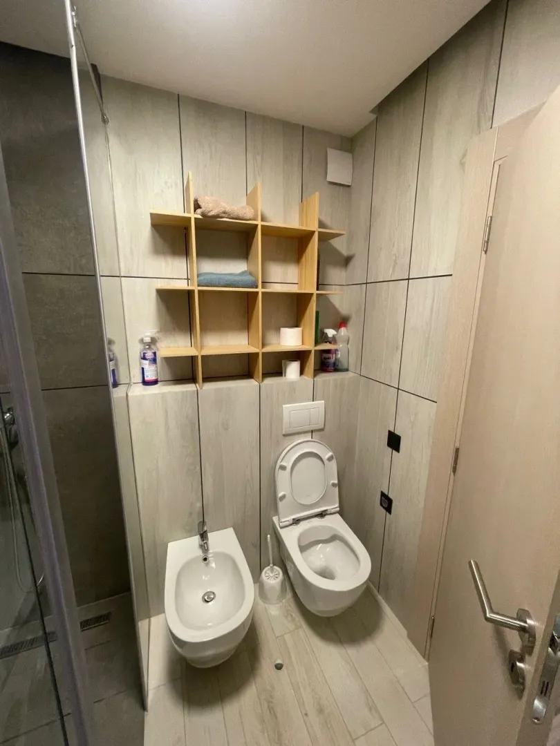 Modernly equipped bathroom with sanitary ware and wooden shelving units.