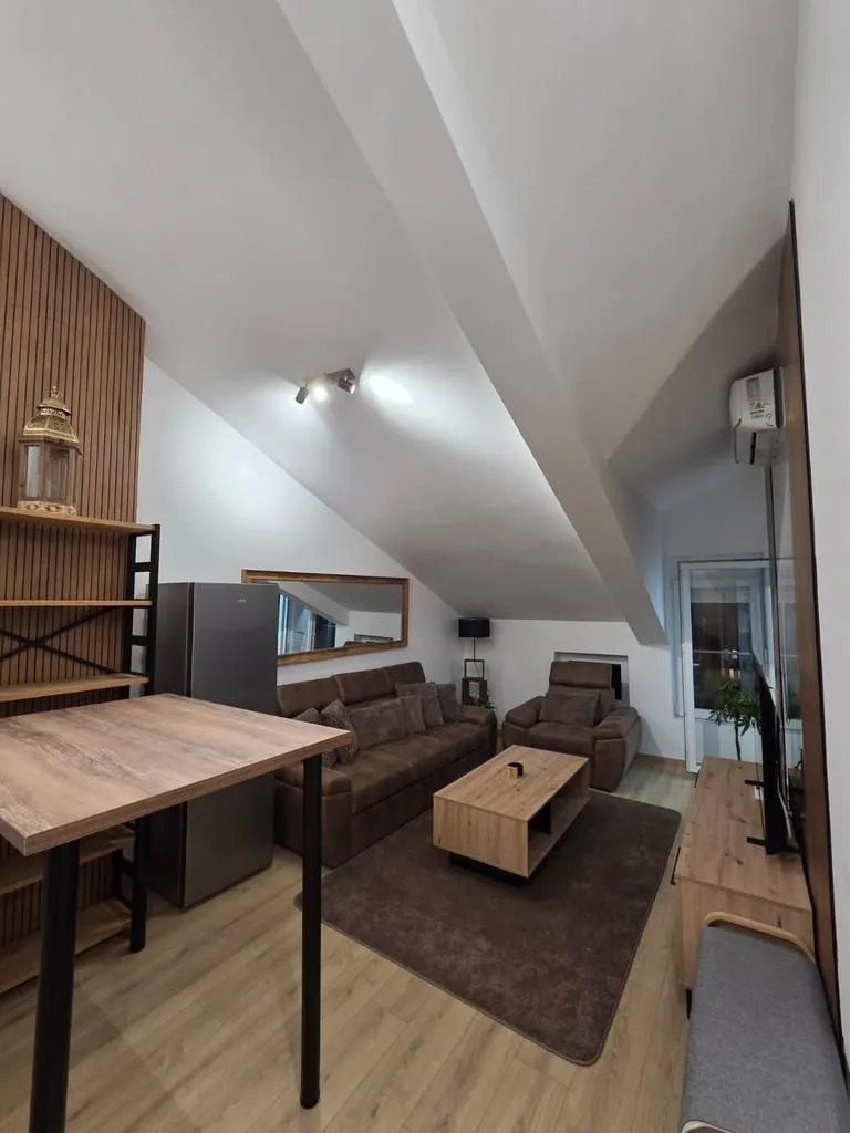 Living room with sofa, dining table and slanted ceilings.