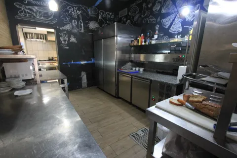 Commercial kitchen with stainless steel work surfaces and refrigerators. - image 16