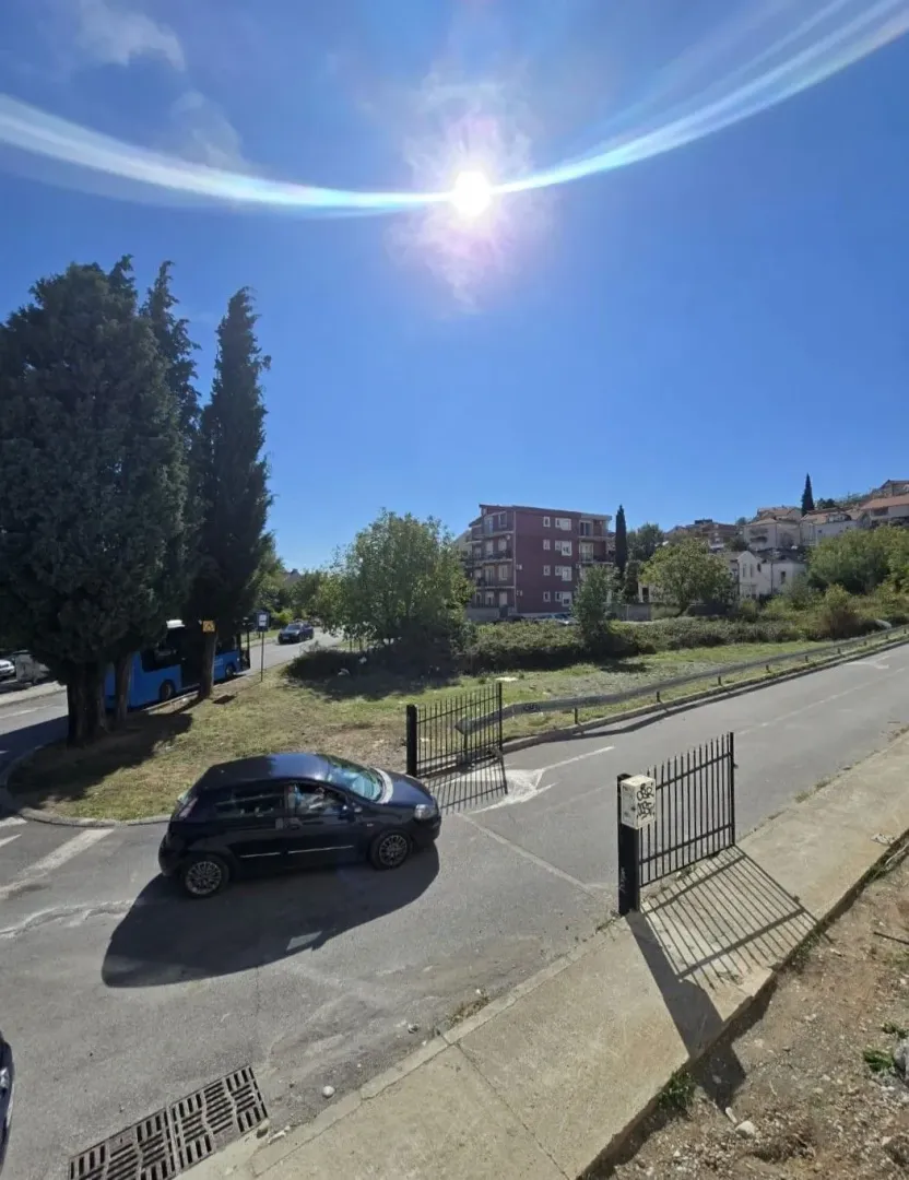 Pogled na ulicu, prilaz i okolne zgrade po sunčanom danu.
