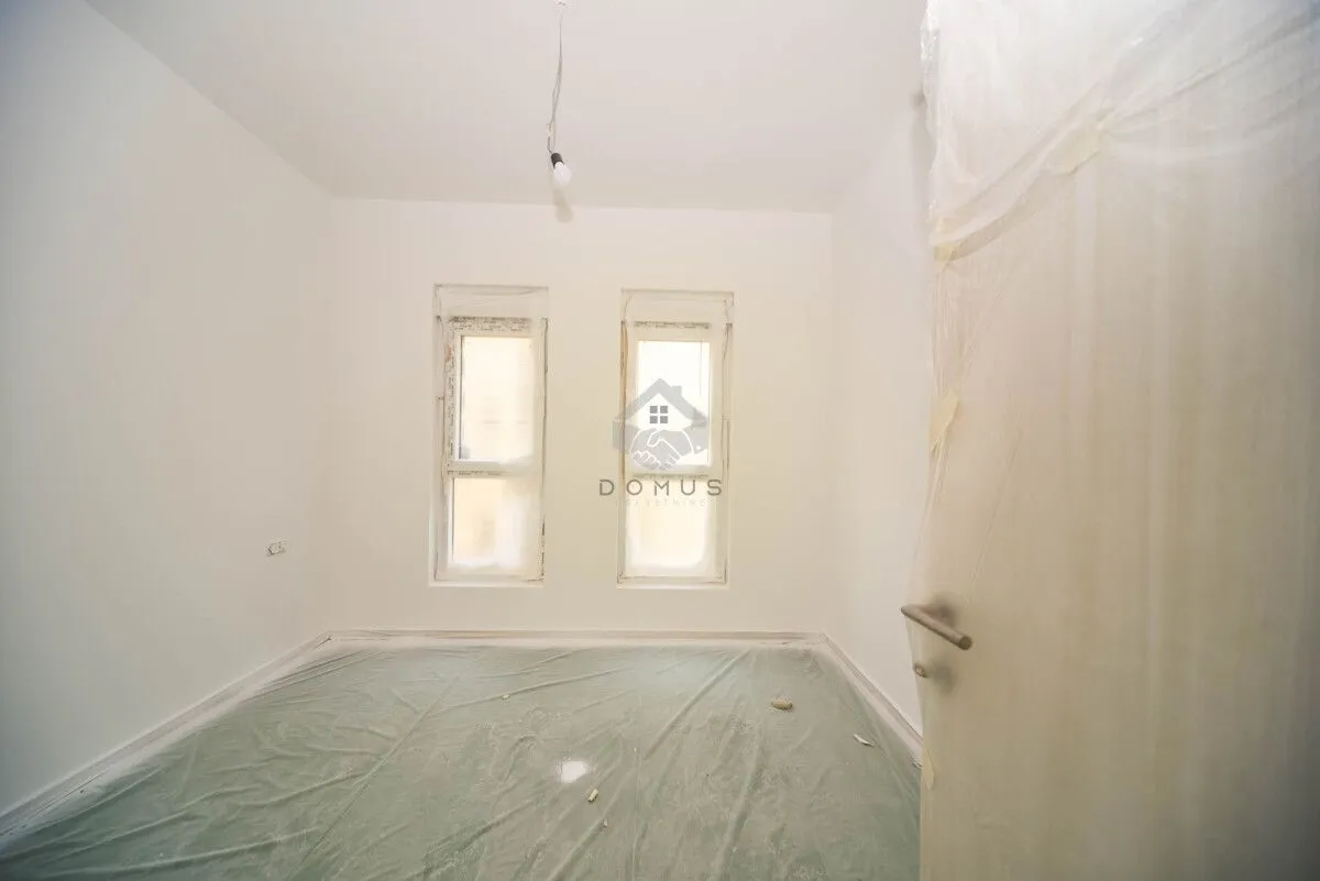 Empty unfinished room with white walls and two windows.