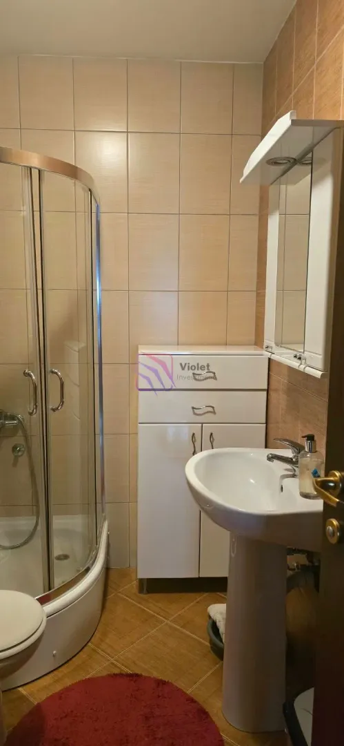 Kupatilo opremljeno tuš kabinom, umivaonikom i ormarićem.