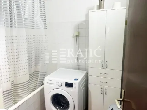 Manje kupatilo sa kadom, veš mašinom i belim ormarićem. - image 13