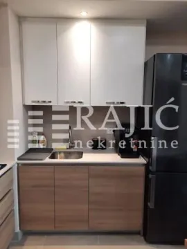 Small kitchen with white upper and wooden lower cabinets and a black refrigerator. - image 4