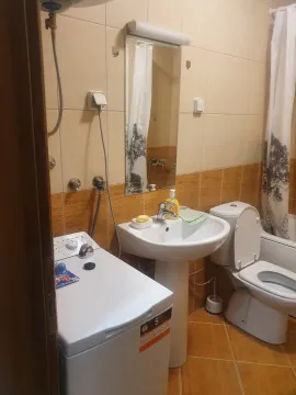 A bathroom with a washing machine, sink, and toilet. - image 5