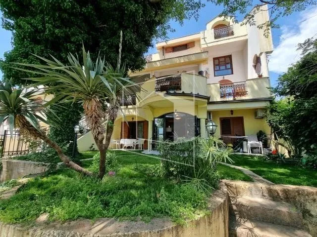 Exterior of a multi-story house with a landscaped yard and greenery.