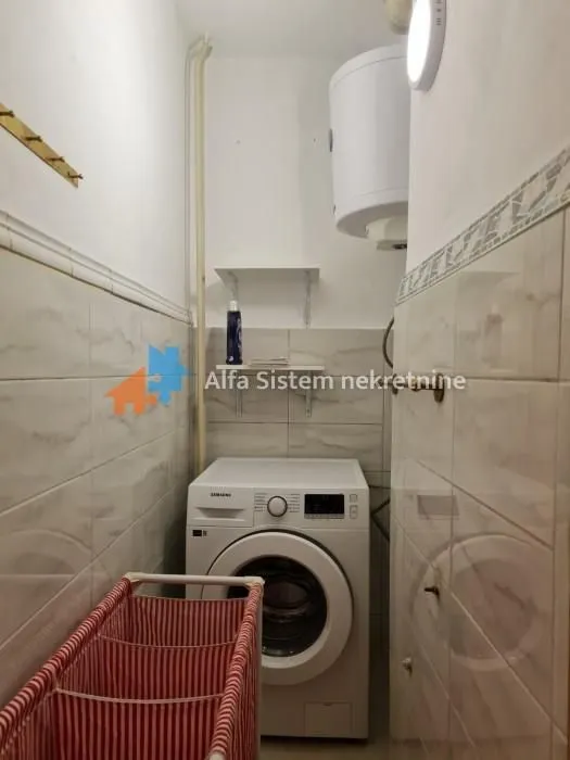 Smaller bathroom with a washing machine and water heater.