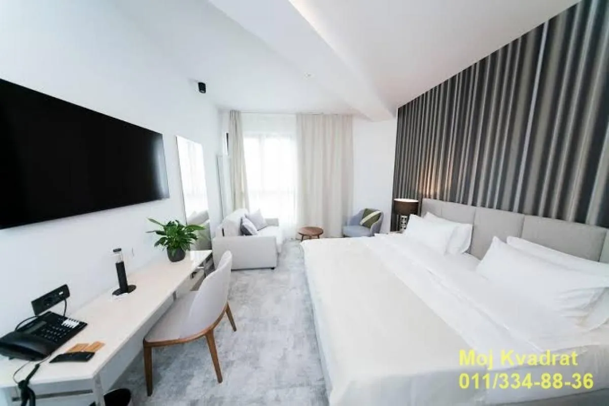 Spacious bedroom with a double bed, desk, and sofa.
