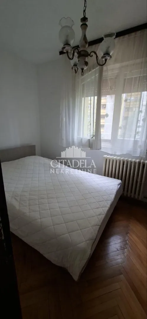 Bedroom with a double bed, window, and chandelier.