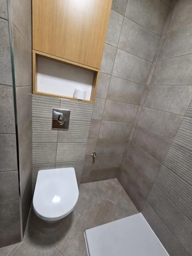 Moderno kupatilo sa wc šoljom i zidnim ormarićem u sivo-bež tonovima.