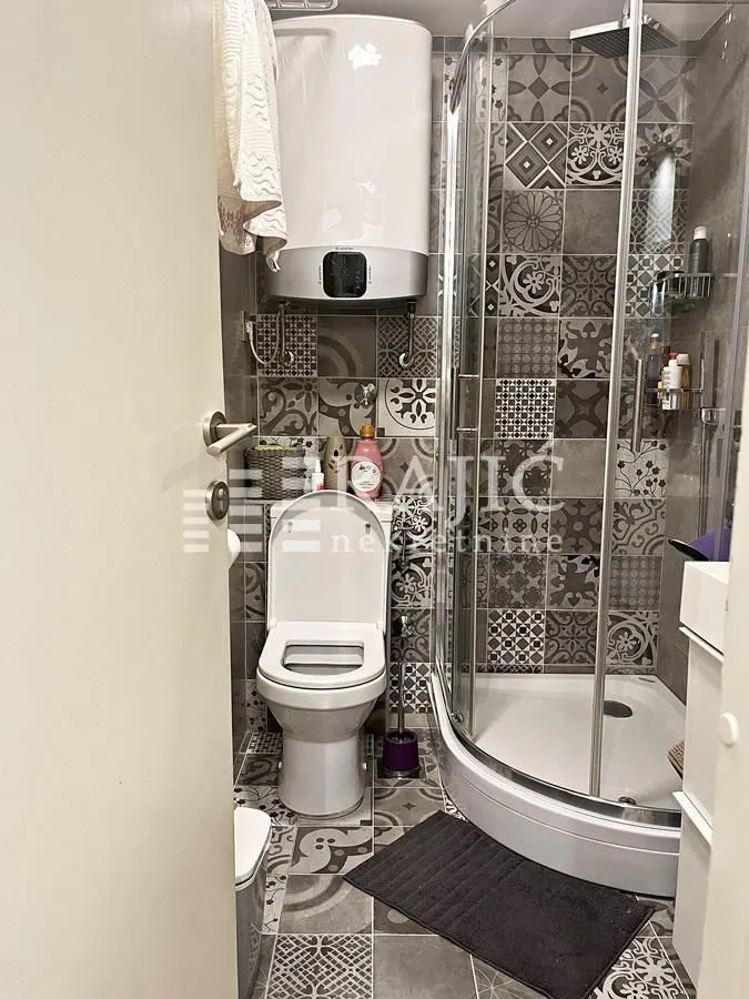 Small bathroom with a shower cabin, toilet, and water heater.