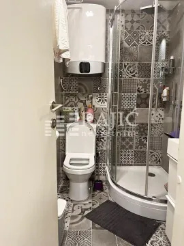 Small bathroom with a shower cabin, toilet, and water heater. - image 9