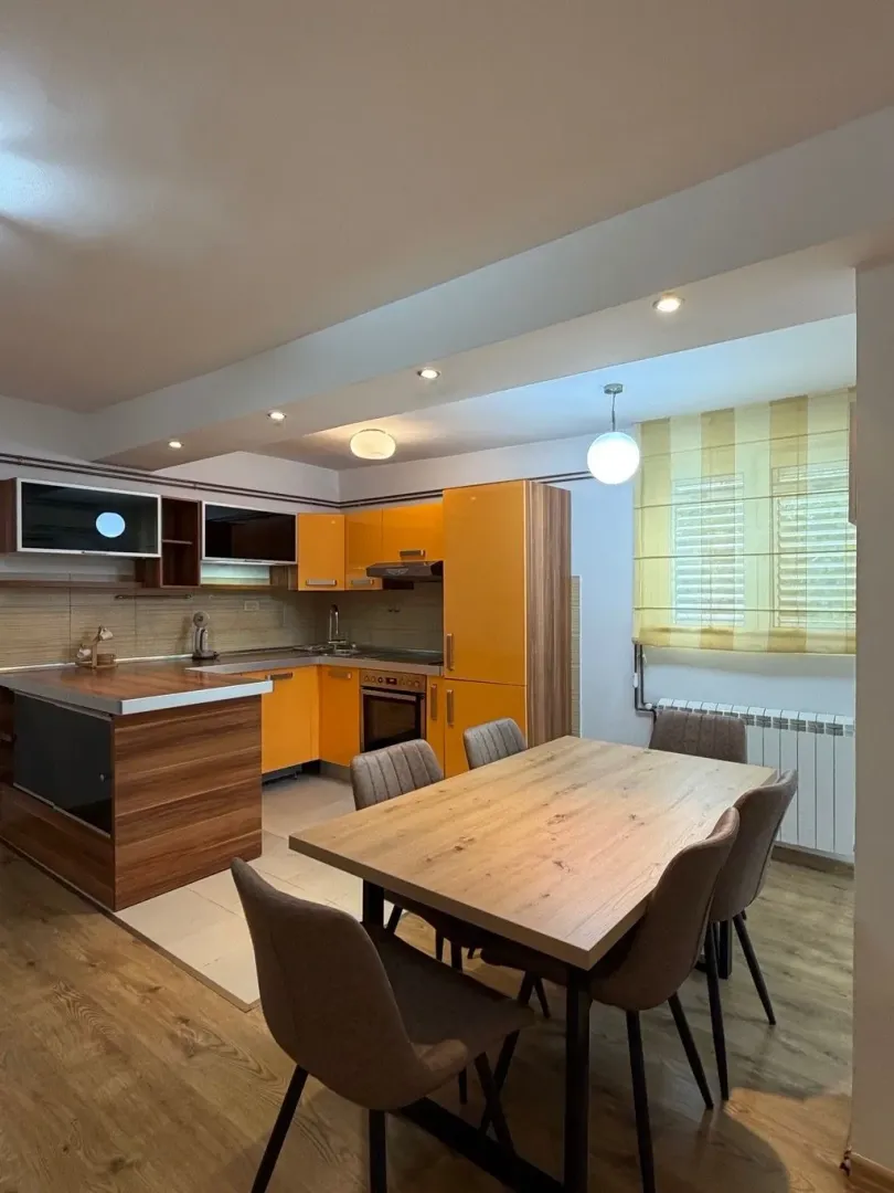 Kitchen with orange units and a dining table.