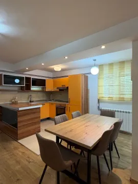 Kitchen with orange units and a dining table. - image 4