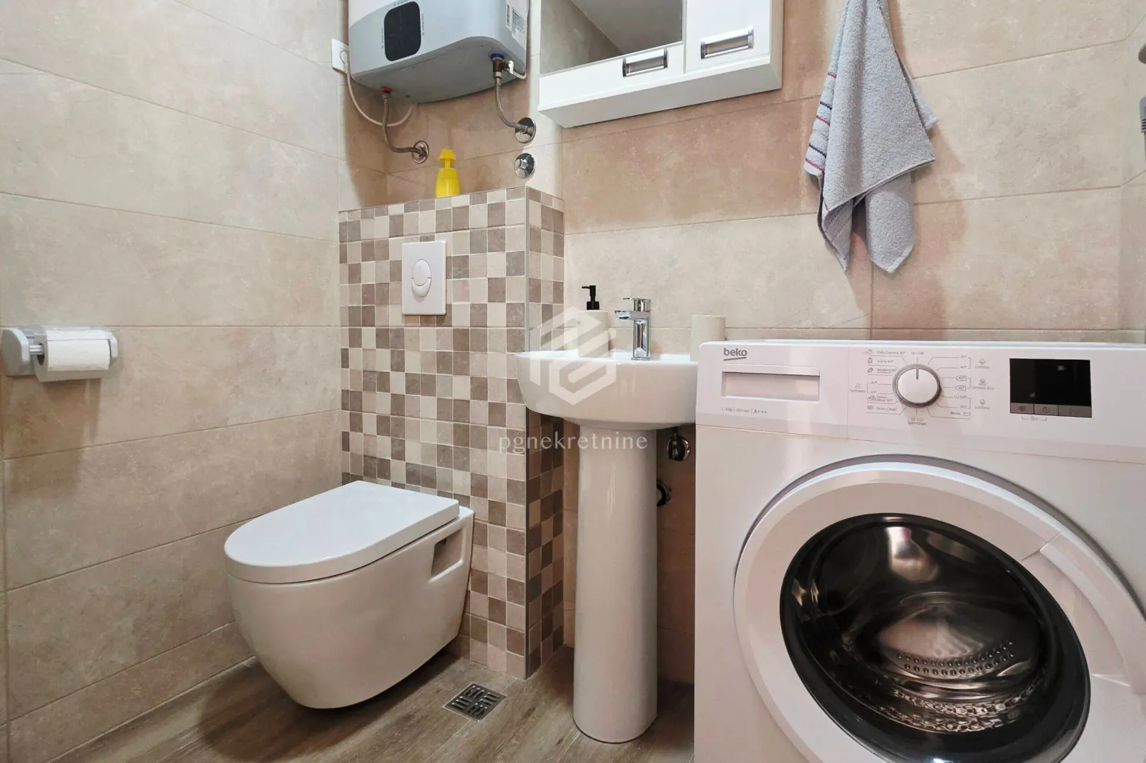 Compact bathroom with a washbasin, toilet, and washing machine.