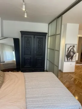Spavaća soba sa bračnim krevetom, tamnim drvenim ormarom i kliznim vratima. - image 10