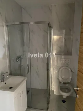 Kupatilo sa tuš kabinom, umivaonikom i toaletom obloženo mermernim pločicama. - image 5