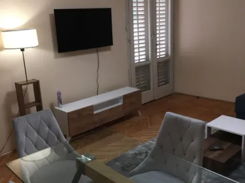 Dnevna soba sa trpezarijskim stolom i stolicama, TV-om i balkonskim vratima. - image 8