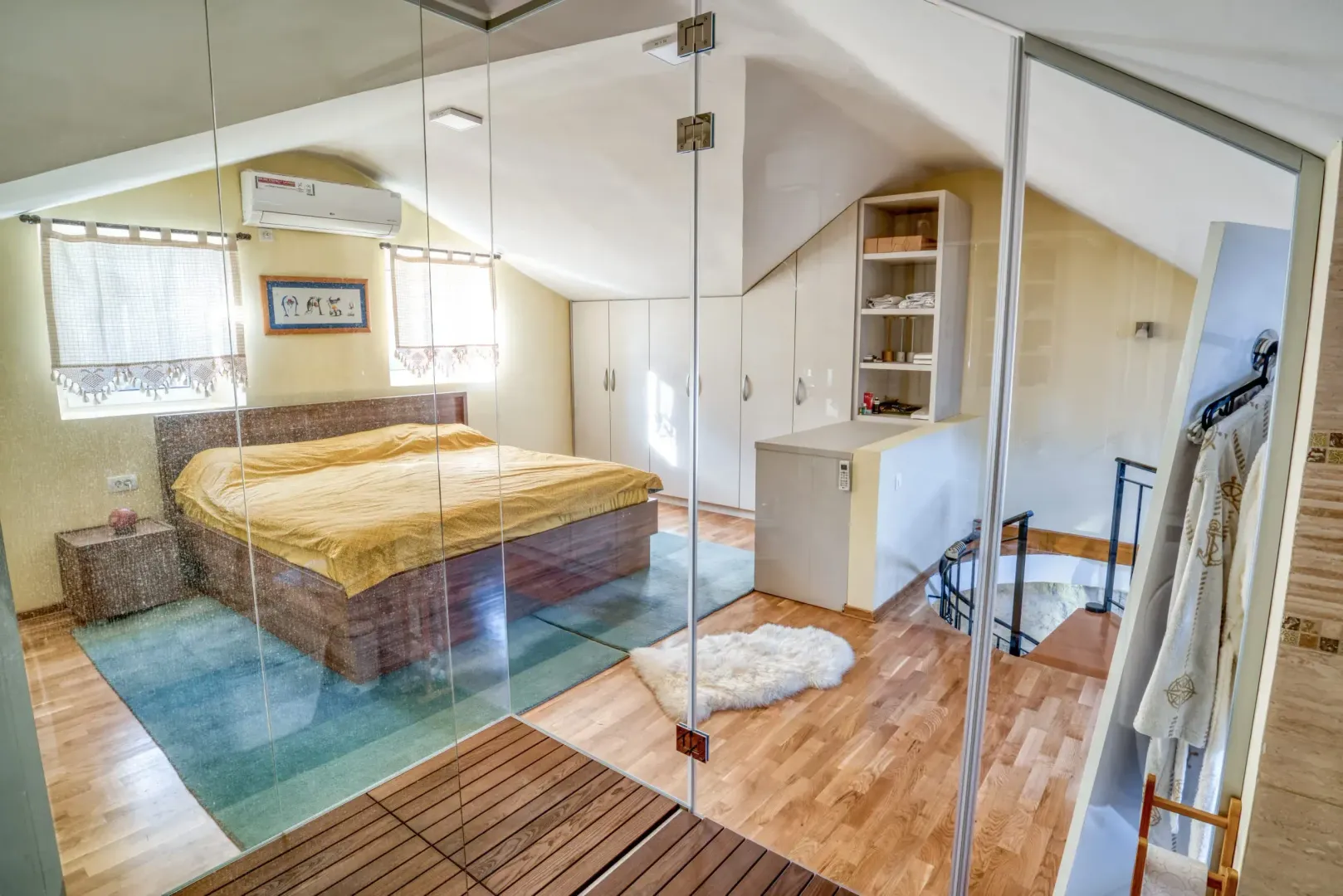 Attic bedroom with a double bed, built-in wardrobes, and a glass partition.