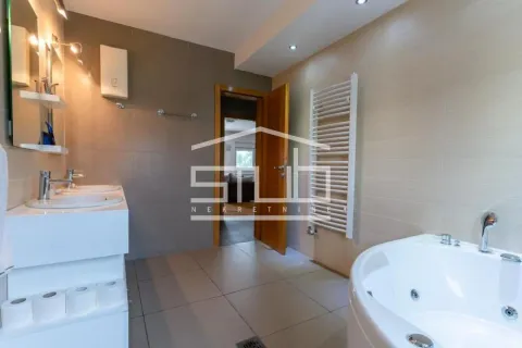 Spacious bathroom with a bathtub, double washbasin and neutral-toned tiles. - image 4